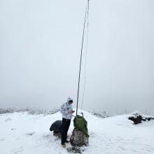 man standing in front of portable ham-radio setup in the snow