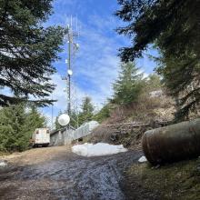 gravel road ending at the top of the hill with trailers and radio tower